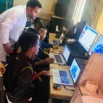3 teacher guiding student on computer